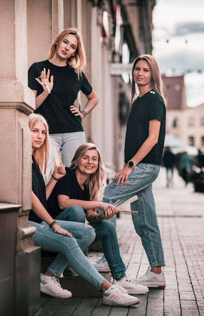 Four women in casual outfits pose confidently on a city street, exuding modern style.